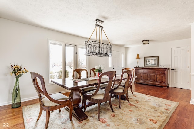 dining room featuring baseboards, a textured ceiling, and wood finished floors