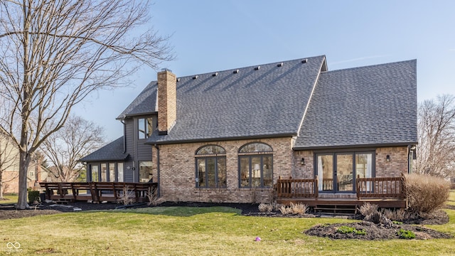 rear view of house featuring roof with shingles, a yard, french doors, a deck, and brick siding