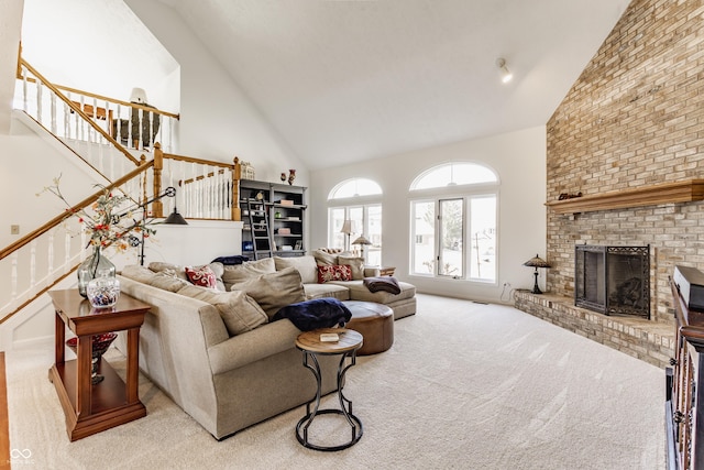 carpeted living room featuring high vaulted ceiling, a fireplace, and stairs