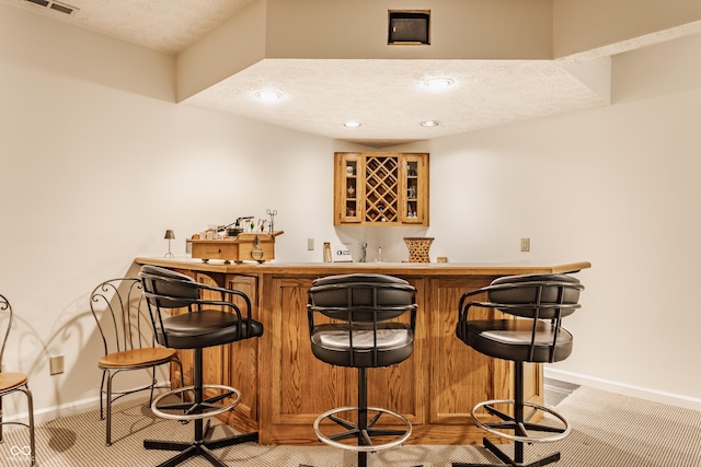 bar with visible vents, baseboards, wet bar, recessed lighting, and a textured ceiling