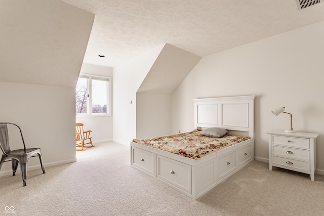 bedroom with visible vents, light colored carpet, a textured ceiling, and vaulted ceiling