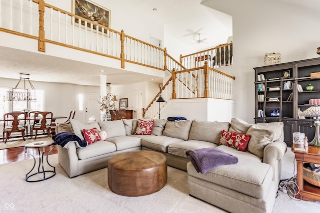 living area featuring ceiling fan, wood finished floors, a towering ceiling, and stairs