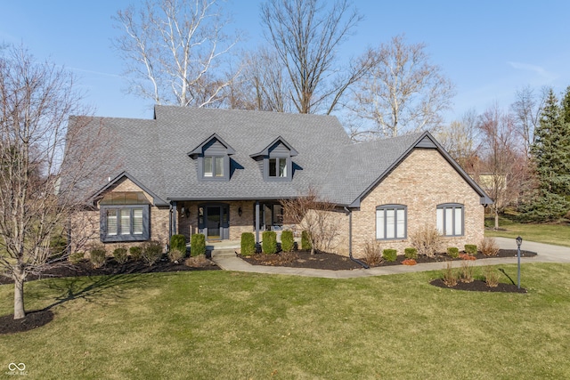 cape cod home featuring a front yard, brick siding, and a shingled roof