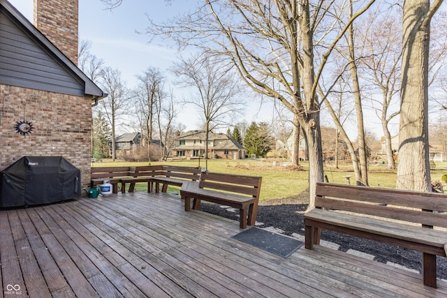 wooden terrace with a lawn and a grill