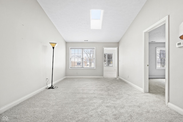 empty room with carpet, a healthy amount of sunlight, baseboards, and a skylight