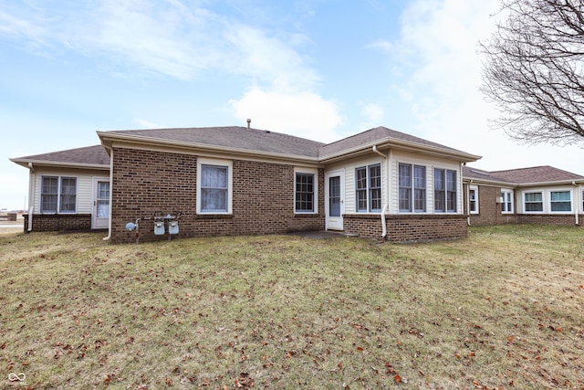 rear view of house featuring a yard and brick siding