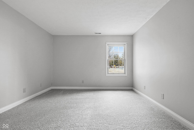 empty room featuring carpet, visible vents, and baseboards