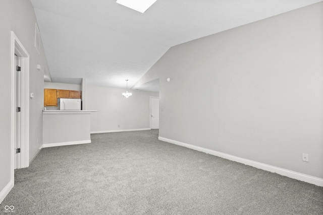 interior space with a chandelier, vaulted ceiling with skylight, carpet floors, and baseboards