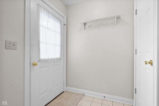 doorway featuring light tile patterned floors and baseboards