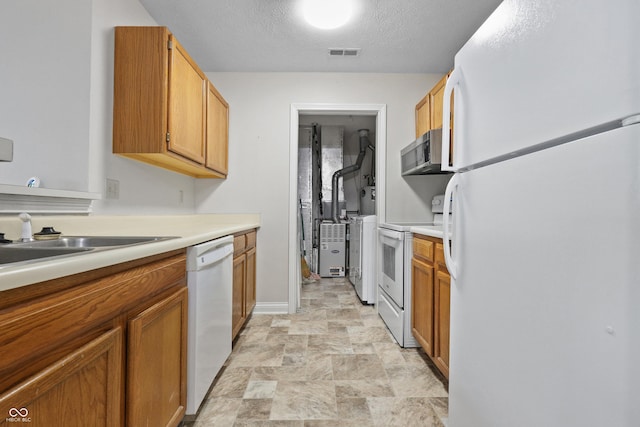 kitchen with brown cabinets, light countertops, visible vents, a textured ceiling, and white appliances