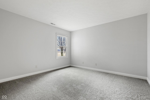 spare room with carpet floors, visible vents, and baseboards