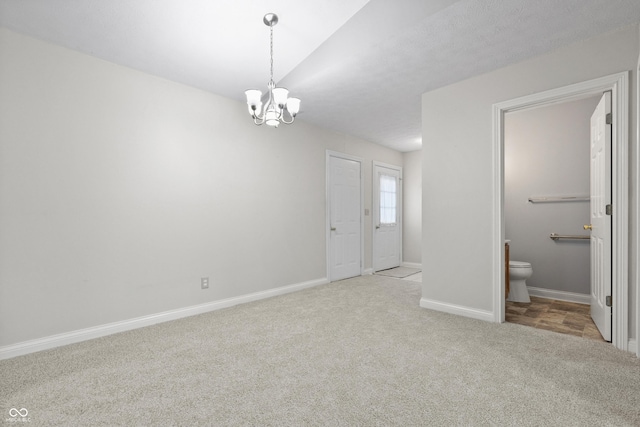 empty room with lofted ceiling, carpet, baseboards, and a notable chandelier