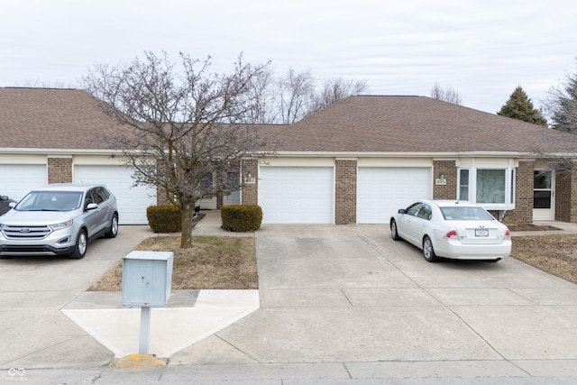 ranch-style home with a garage, brick siding, driveway, and a shingled roof