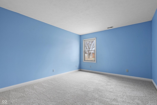 empty room with carpet floors, baseboards, visible vents, and a textured ceiling