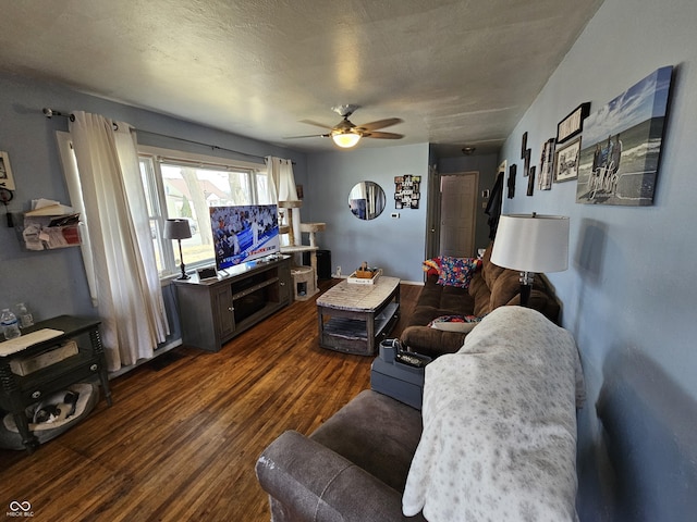 living room with ceiling fan, a textured ceiling, and dark wood finished floors