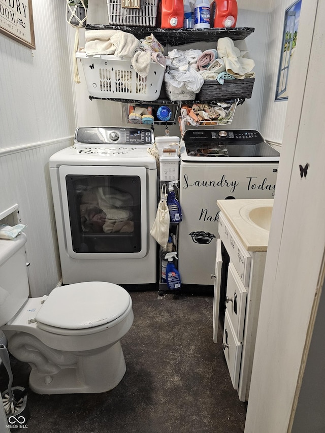 bathroom with toilet, vanity, washer and clothes dryer, and wainscoting