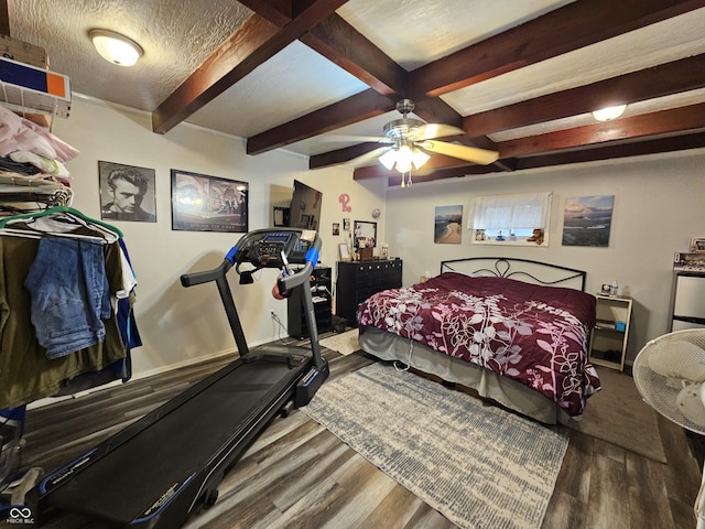 bedroom with a textured ceiling, wood finished floors, a ceiling fan, baseboards, and beam ceiling