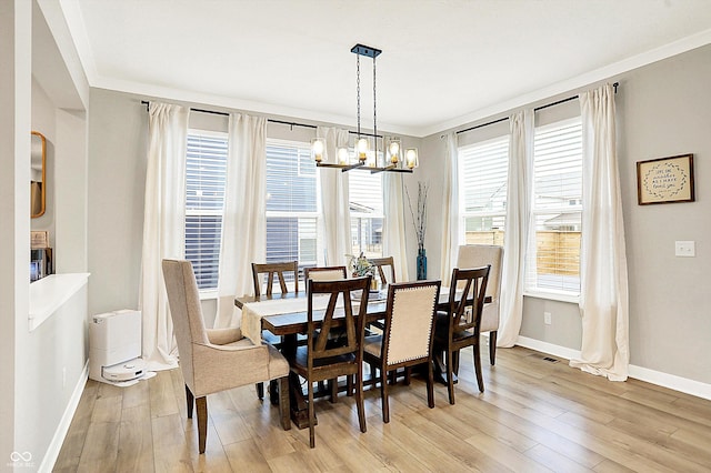 dining area featuring light wood-style flooring, a notable chandelier, visible vents, baseboards, and ornamental molding