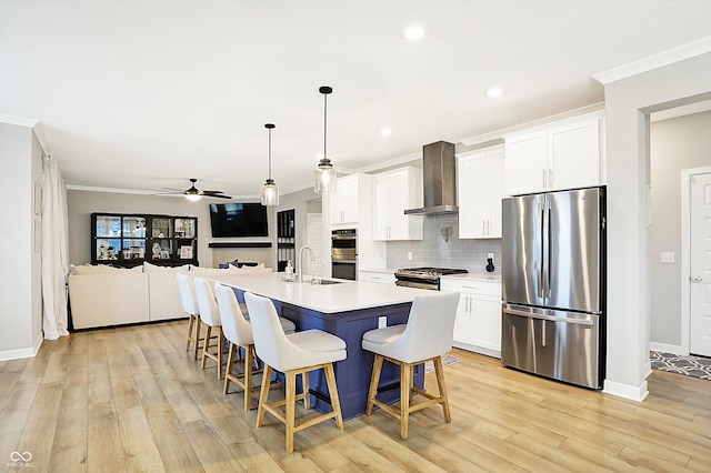 kitchen with wall chimney exhaust hood, crown molding, appliances with stainless steel finishes, and a sink