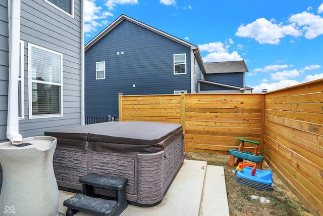 view of patio featuring fence and a hot tub