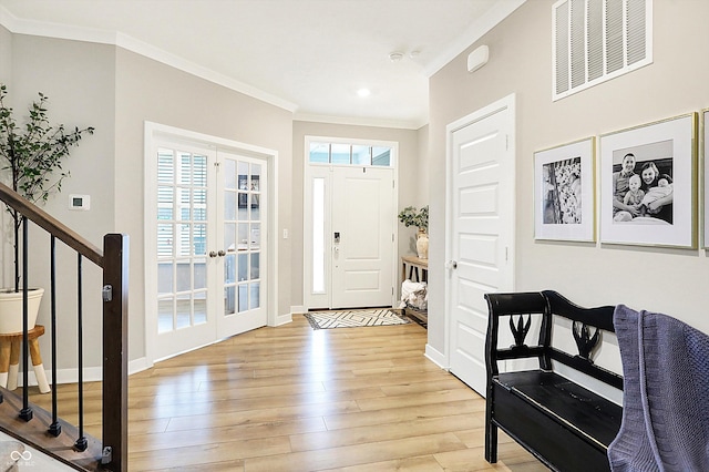 foyer featuring visible vents, baseboards, stairs, ornamental molding, and light wood-type flooring