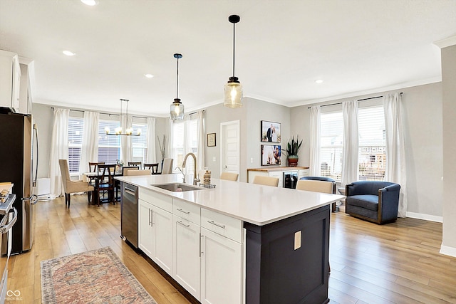 kitchen featuring light wood-type flooring, appliances with stainless steel finishes, a sink, and ornamental molding