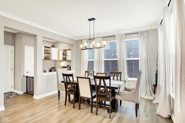 dining room with light wood-style floors, crown molding, a notable chandelier, and baseboards