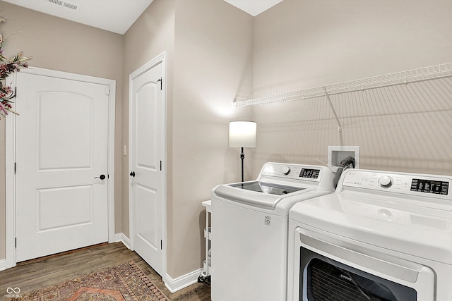 washroom featuring laundry area, wood finished floors, washing machine and dryer, and baseboards