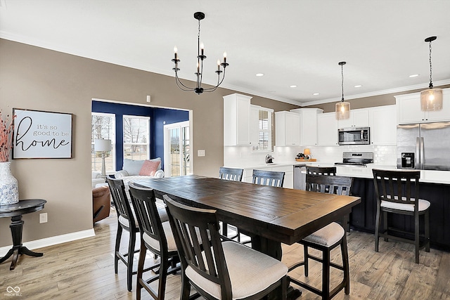 dining area with light wood-type flooring, a healthy amount of sunlight, baseboards, and crown molding