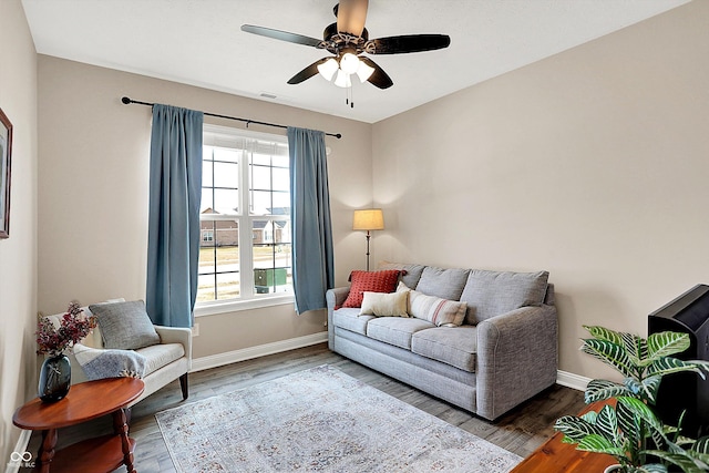 living area featuring a ceiling fan, baseboards, and wood finished floors