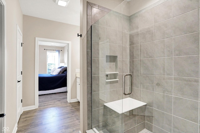 ensuite bathroom featuring a stall shower, baseboards, ensuite bathroom, and wood finished floors