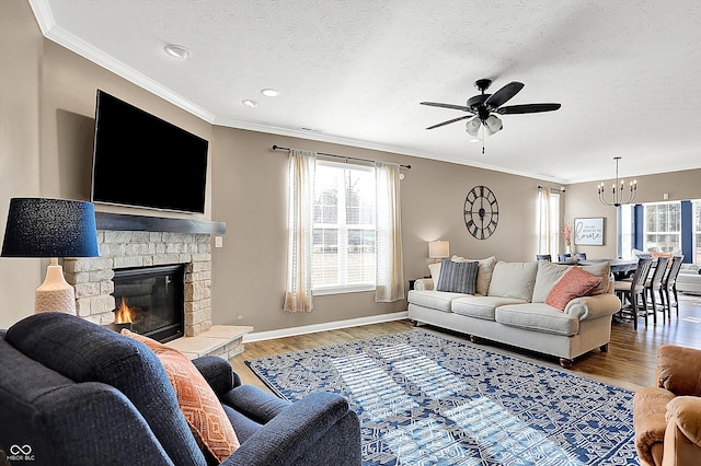 living room featuring ornamental molding, a stone fireplace, baseboards, and wood finished floors