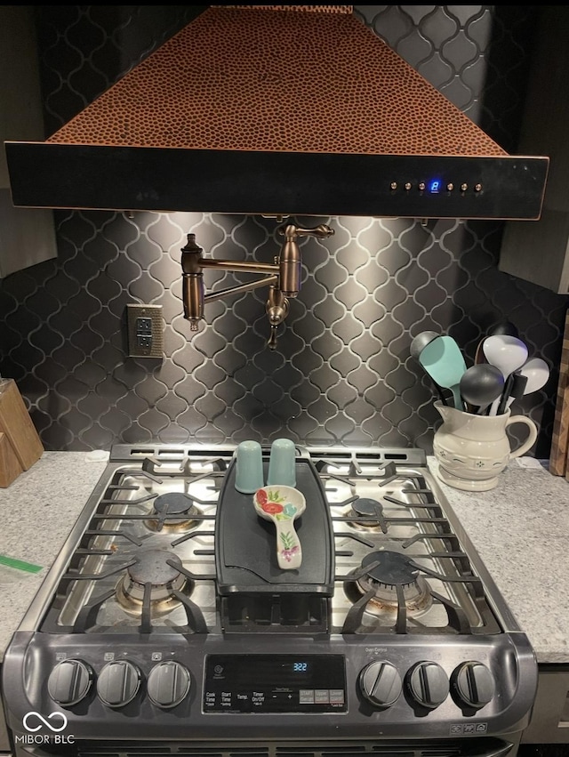 kitchen featuring stainless steel gas range oven, custom exhaust hood, light countertops, and backsplash