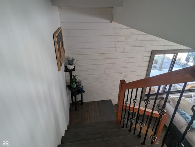 stairs with wooden walls and wood finished floors