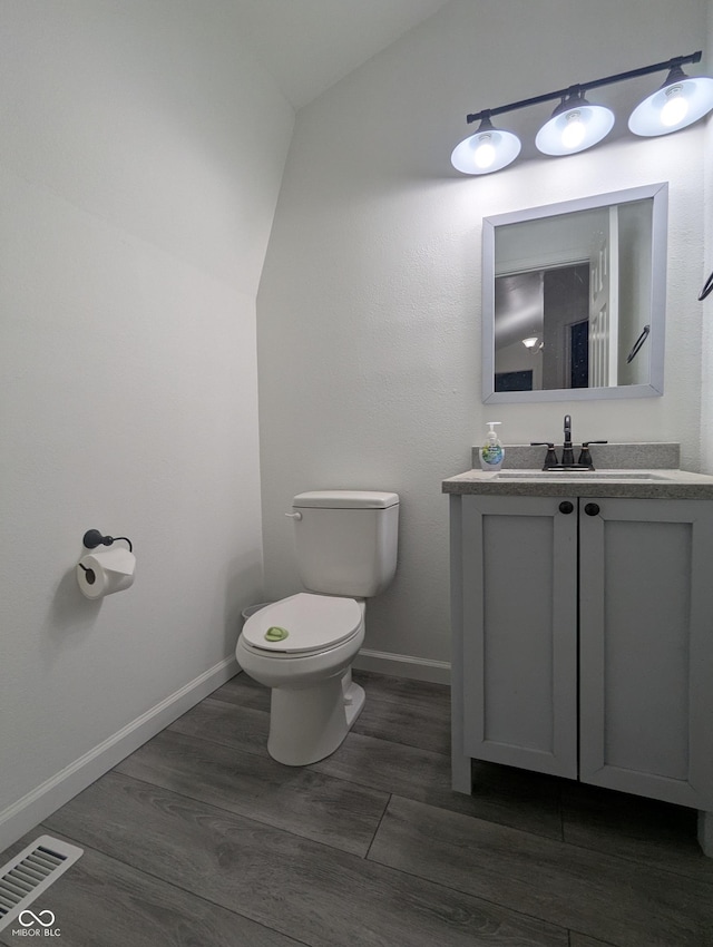 bathroom featuring visible vents, toilet, wood finished floors, vaulted ceiling, and vanity