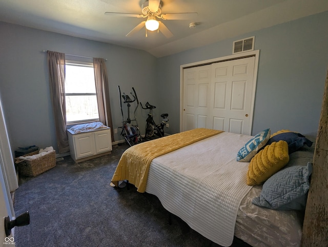 bedroom featuring ceiling fan, visible vents, vaulted ceiling, a closet, and dark colored carpet