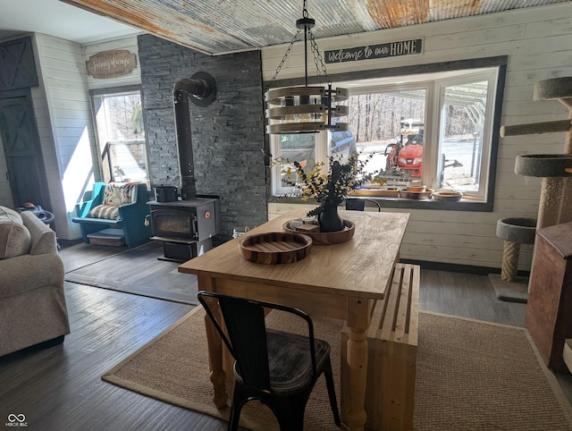 dining room with a wood stove, wood walls, and wood-type flooring