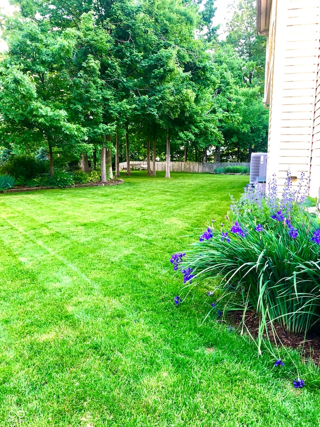 view of yard featuring central AC and fence