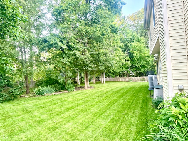 view of yard featuring central AC and fence