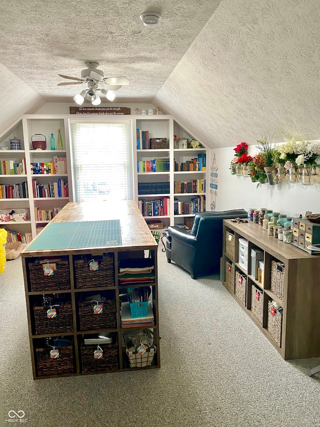 office area featuring lofted ceiling, a textured ceiling, carpet, and a ceiling fan