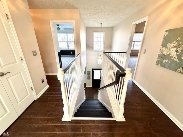 staircase featuring baseboards, a textured ceiling, and wood tiled floor