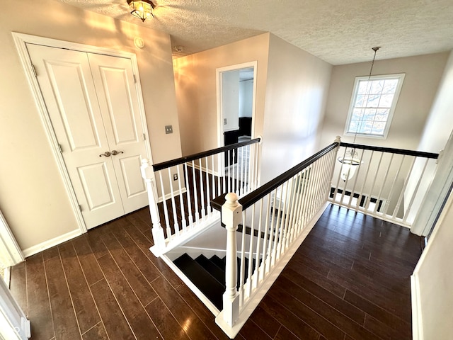 stairway featuring a textured ceiling, wood finished floors, and baseboards