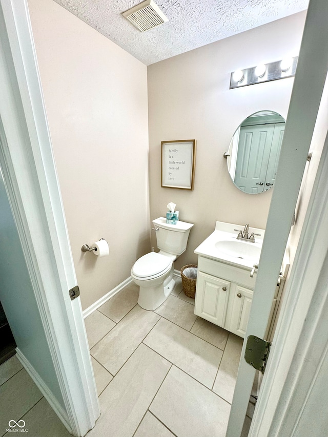 half bathroom with a textured ceiling, toilet, vanity, visible vents, and tile patterned floors