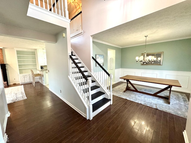 staircase with a textured ceiling, wainscoting, wood-type flooring, and crown molding