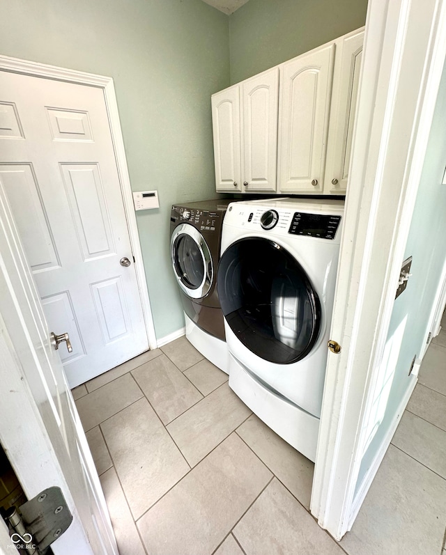 laundry room with washing machine and dryer, cabinet space, baseboards, and light tile patterned floors