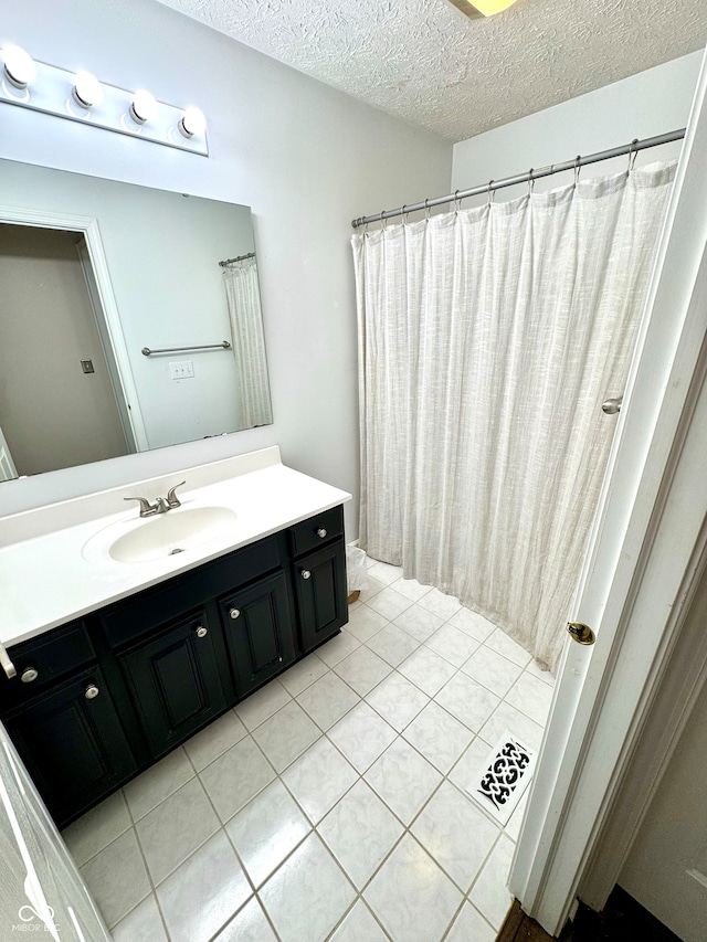 bathroom featuring tile patterned flooring, visible vents, vanity, and a textured ceiling