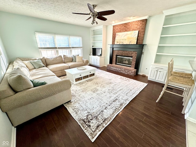 living room featuring a textured ceiling, a brick fireplace, dark wood finished floors, and built in features