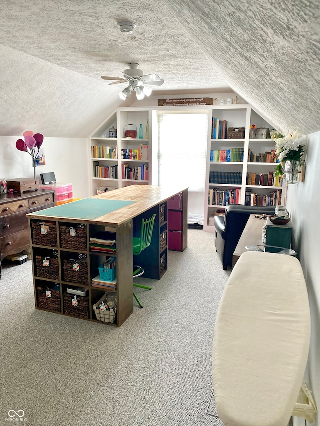 office space with ceiling fan, vaulted ceiling, a textured ceiling, carpet floors, and built in shelves