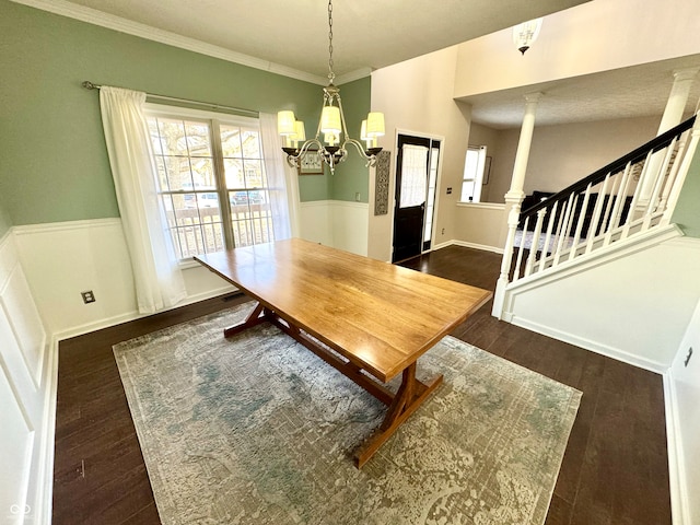 dining room featuring crown molding, wood finished floors, stairs, wainscoting, and an inviting chandelier