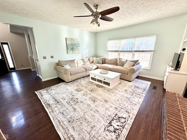 living area with a ceiling fan, dark wood finished floors, a textured ceiling, and baseboards